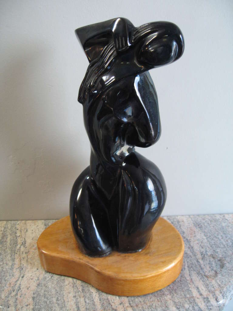 Superb modernist female form sculpture, dating to the late 1940's. Rendered in an art deco motif, this sculpture is made of a dense, high glazed solid porcelain. Very heavy and well made, with an amorphic blonde wood base. 

Signed. and exhibited