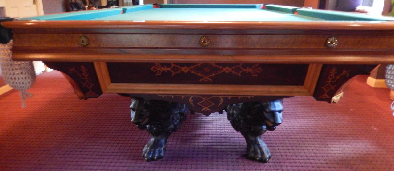 Superbly rare, this imposing Monarch Model Brunswick billiard table dates to circa 1880 and is comprised of inlaid woods including ash and maple burl, Brazilian rosewood, ebony and tulip wood. 

Base is made of cast iron lion form supports. Rare 9