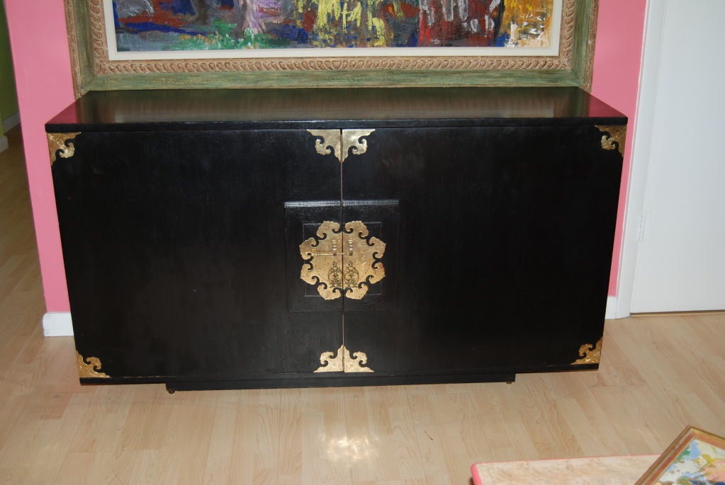 Midcentury Asian inspired sideboard with decorative brass hardware  and petite brass feet.Nice original ebony stained finish.Perfect for many applications including storing electronic equipment or utilize in dining or bedroom as desired.