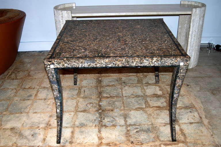 Maitland Smith tessellated marble game table executed in tones of brown and cream with black banding accents on top and legs as shown.