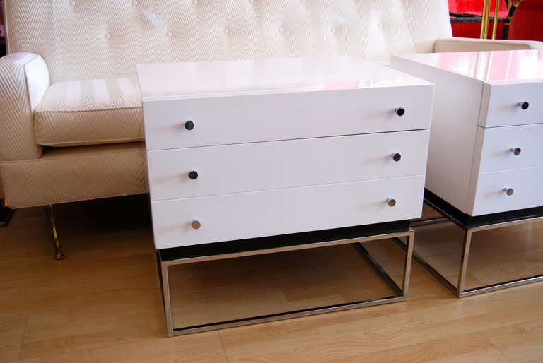 Wonderful! Simplistic pair of Milo Baughman nightstands/end tables executed in white lacquer. Tables consist of two drawers with a lower double deep drawer for excellent storage. Frames and circular pulls are featured in polished chrome . Tables are