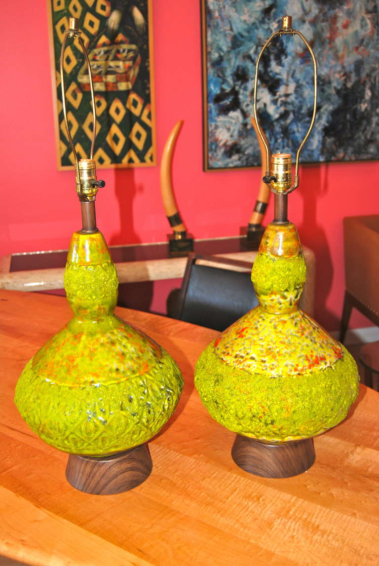 Interesting pair of highly textured pottery lamps executed in an earthenware tone of dark pear with hints of orange and brown.  Great mixture of glazed pottery at the neck and lower section of the lamp. The center portion of each lamps has a