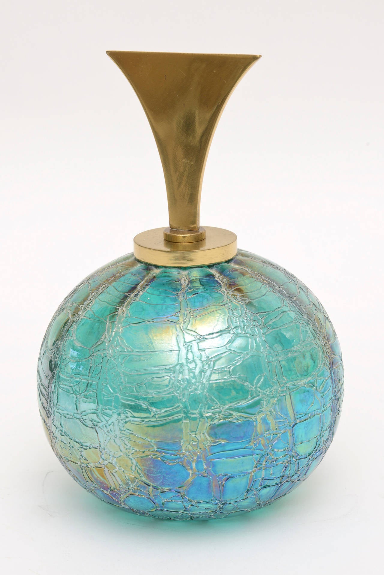 The luscious color of this Tiffany style glass bottle/object being predominately a rich turquoise with iridescence fading to other shades to blue at the bottom.. it is a showstopper!! The original polished brass stopper/top adds a sculptural