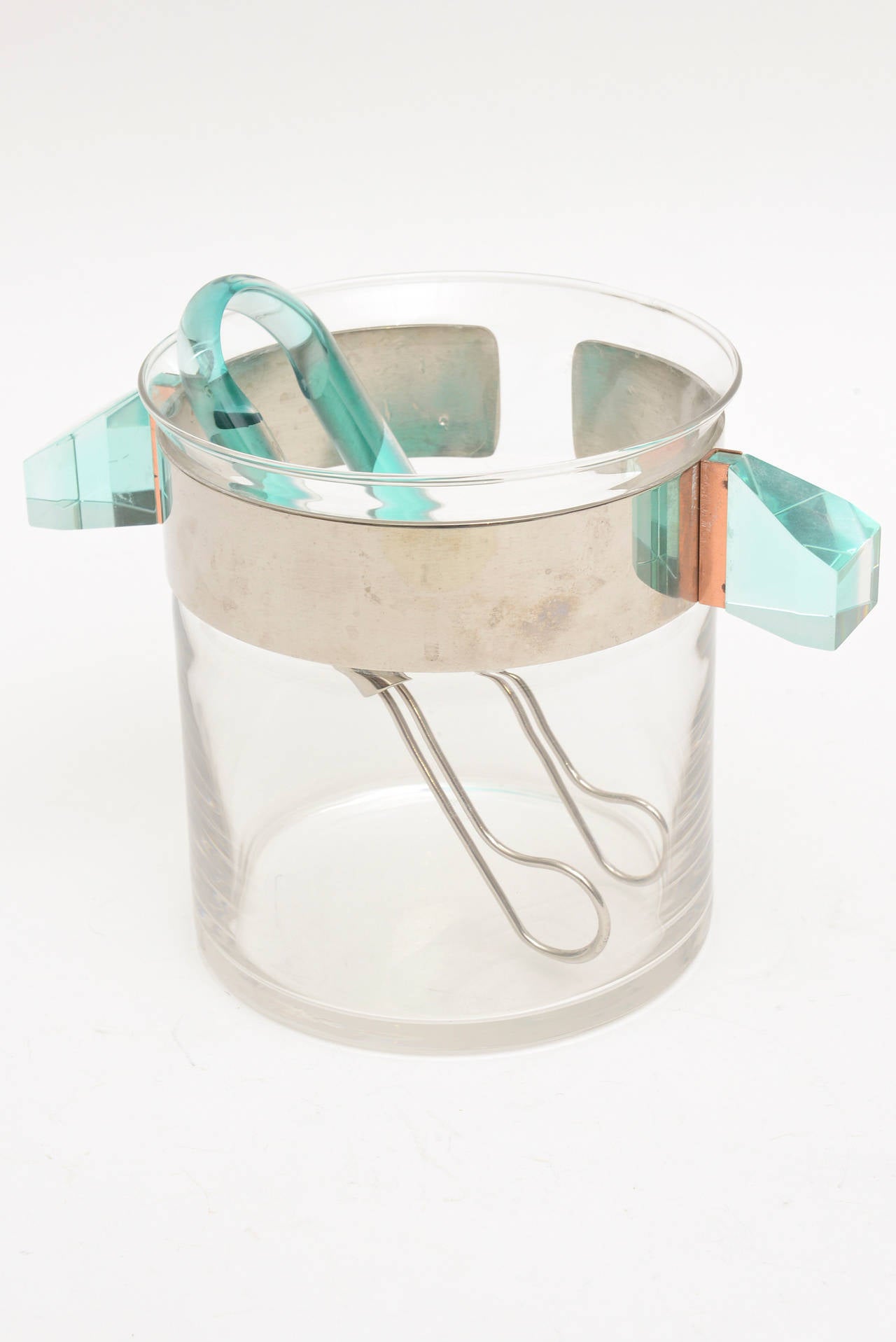 This fantastic Italian unusual and rare ice bucket is signed by Rede Guzzini.
Handmade in Italy.
The round cylinder is glass with brilliant colored Lucite handles in turquoise sea green. It is connected with copper on the handles and a chrome band