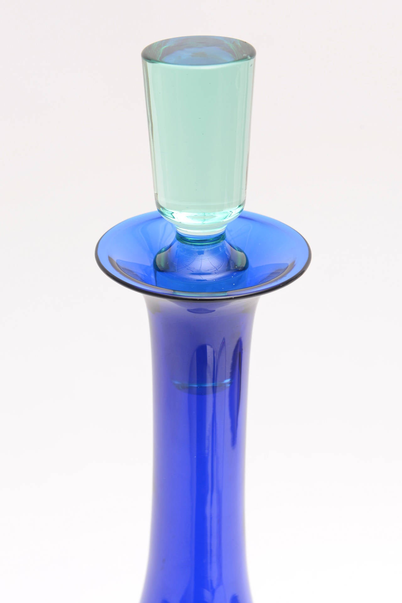 This danish gorgeous glass bottle/decanter/object has rich arresting colors that are layered and sommerso. it is by Anje Kjaer for Holmegaard/Royal Copenhagen
Royal blue fades to darker midnight blue/black to sea blue green...
The original stopper