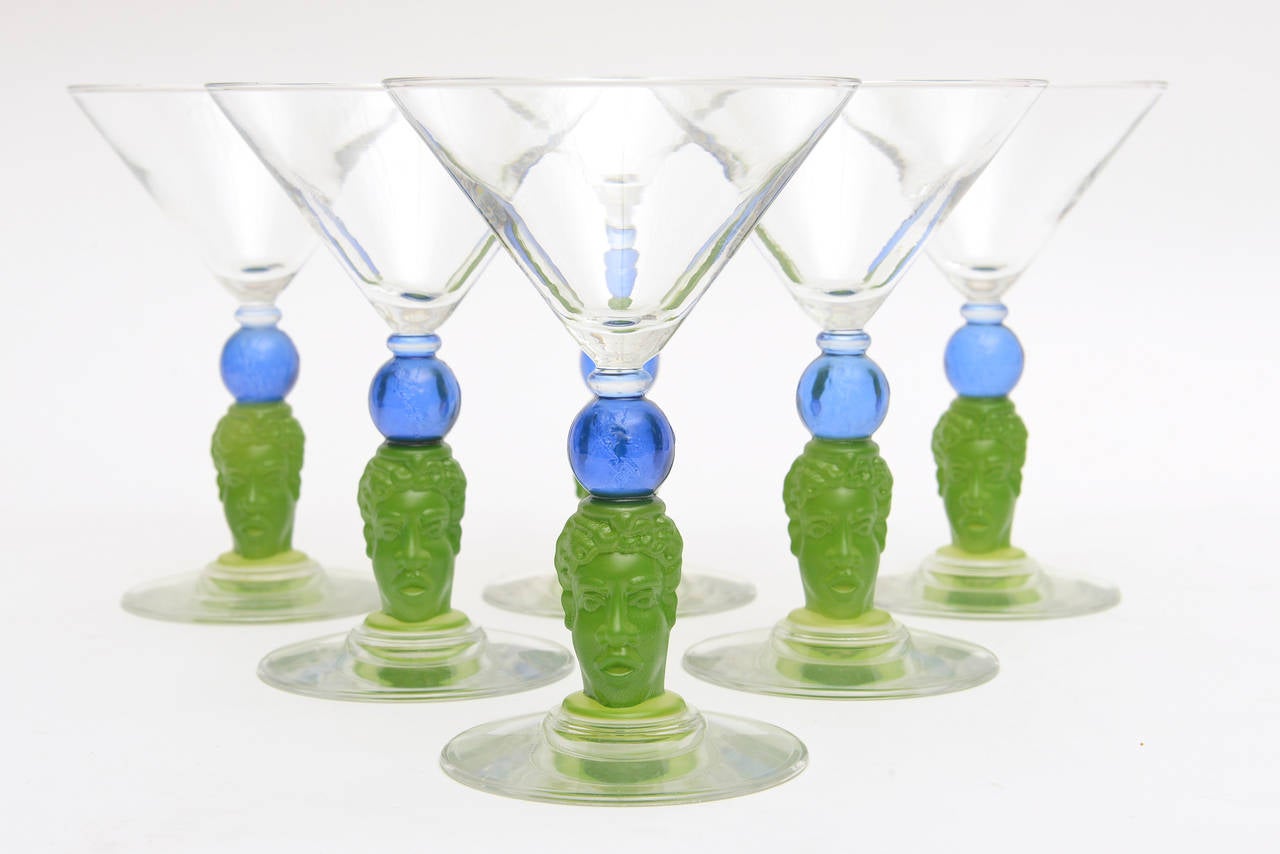 Chic, artful... these six perfect sculptural signed all glass barware by Richard Jolley are in beautiful hues of green and blue glass with clear top and bottom.
The stem is a carved face that he is known for. These were a limited edition for
