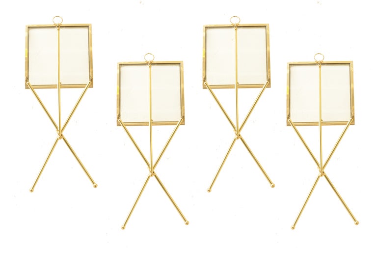 These very clever and chic tripod brass and glass folding drink tables by the company Chapman have the 3 legs with ball feet and a ring suspending from one corner.
They all fold up and can be hung on a wall as a sculptural installation for further