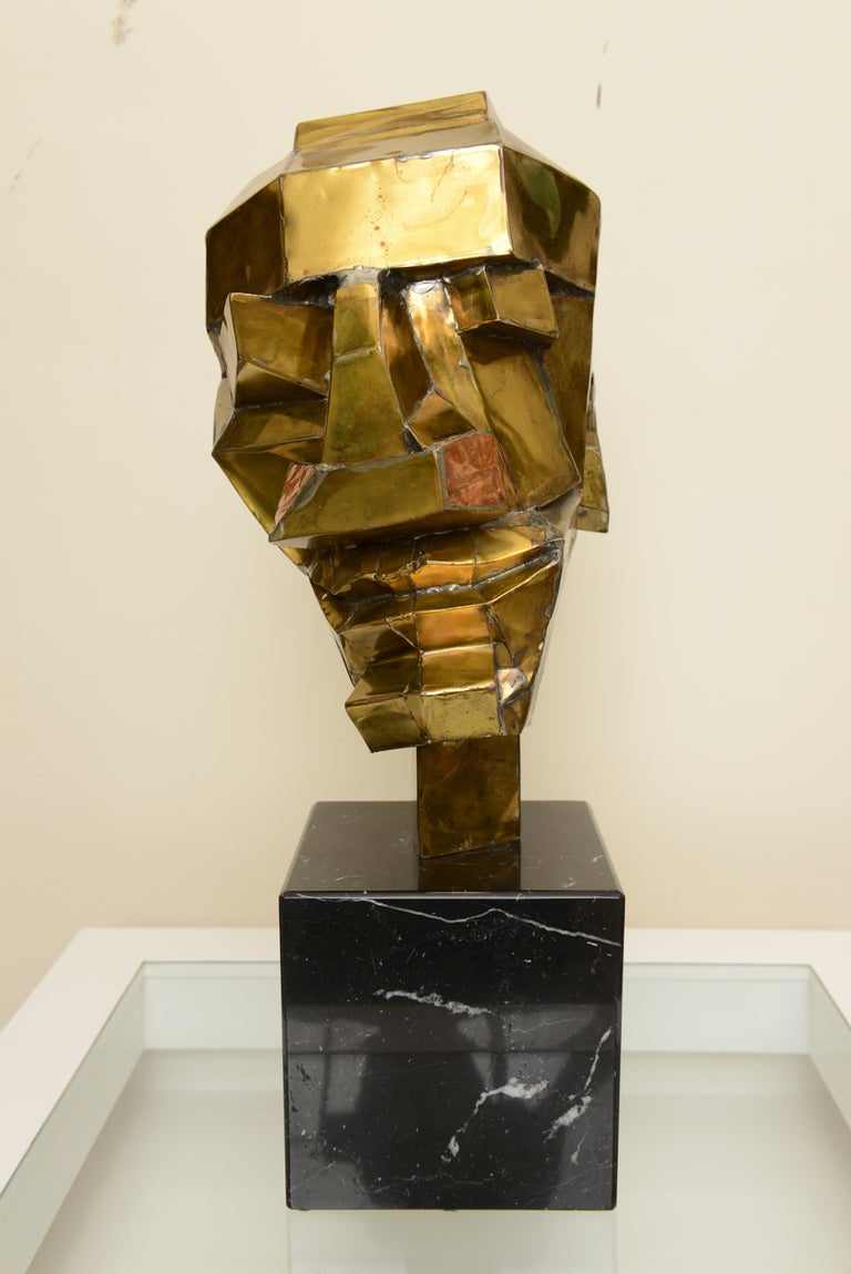 This very unusual half cocked male one of a kind sculpture has one ear with it's torched brass brutalist cubist  dimensional abstracted
form and shape.His head is torched brass and he sits on a solid black marble base.
Monumental in presence and