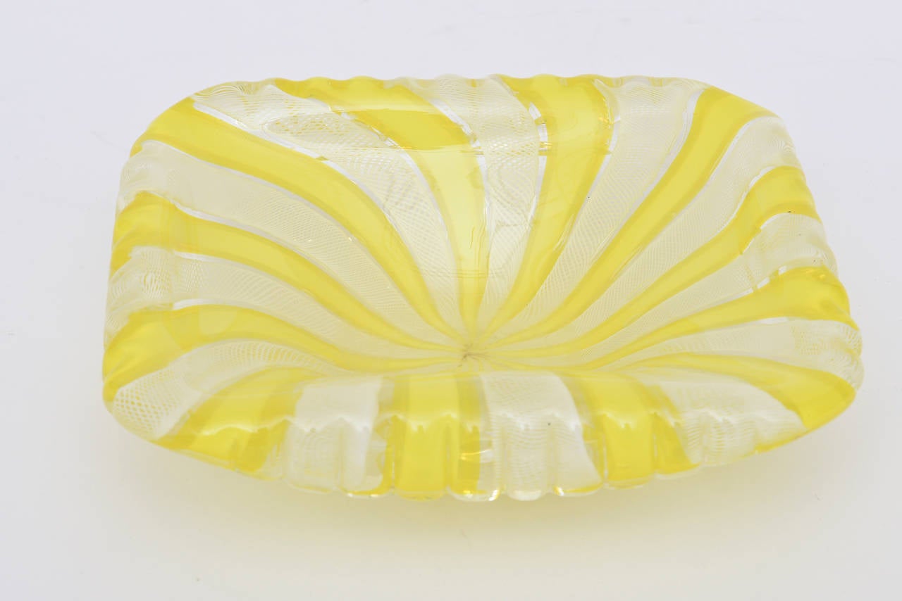 Spring is here, with the happy and brilliant colors of the yellow pinwheel effect stripes against the white latticino in this beautiful Italian Murano glass square bowl by Fratelli Toso. Great for serving...
It is folded slightly under as a lip on