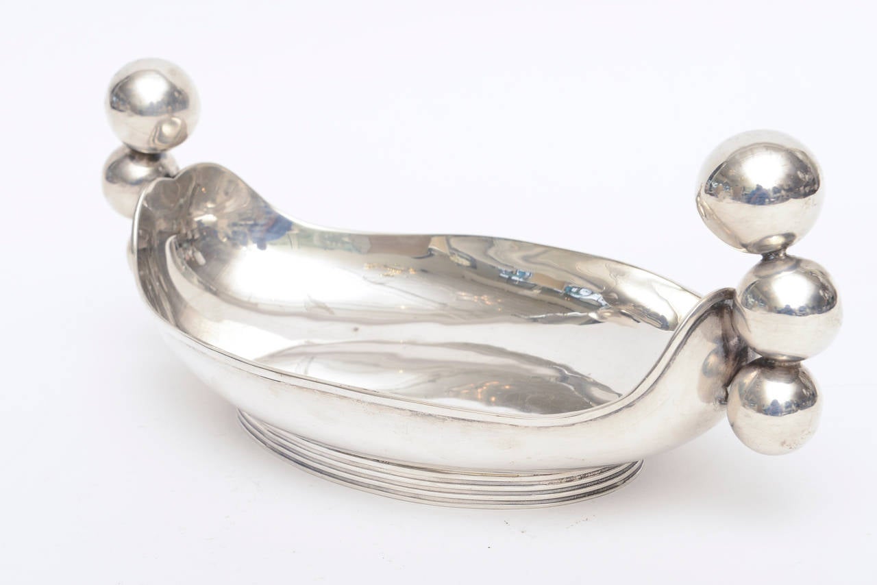 This wonderful signed Mexican sterling silver serving bowl or bowl has three graceful big balls on either side that act as handles and sculptural forms.
It is hallmarked C.Zurita Hencho en Mexico on the bottom. He was a wonderful metalsmith from