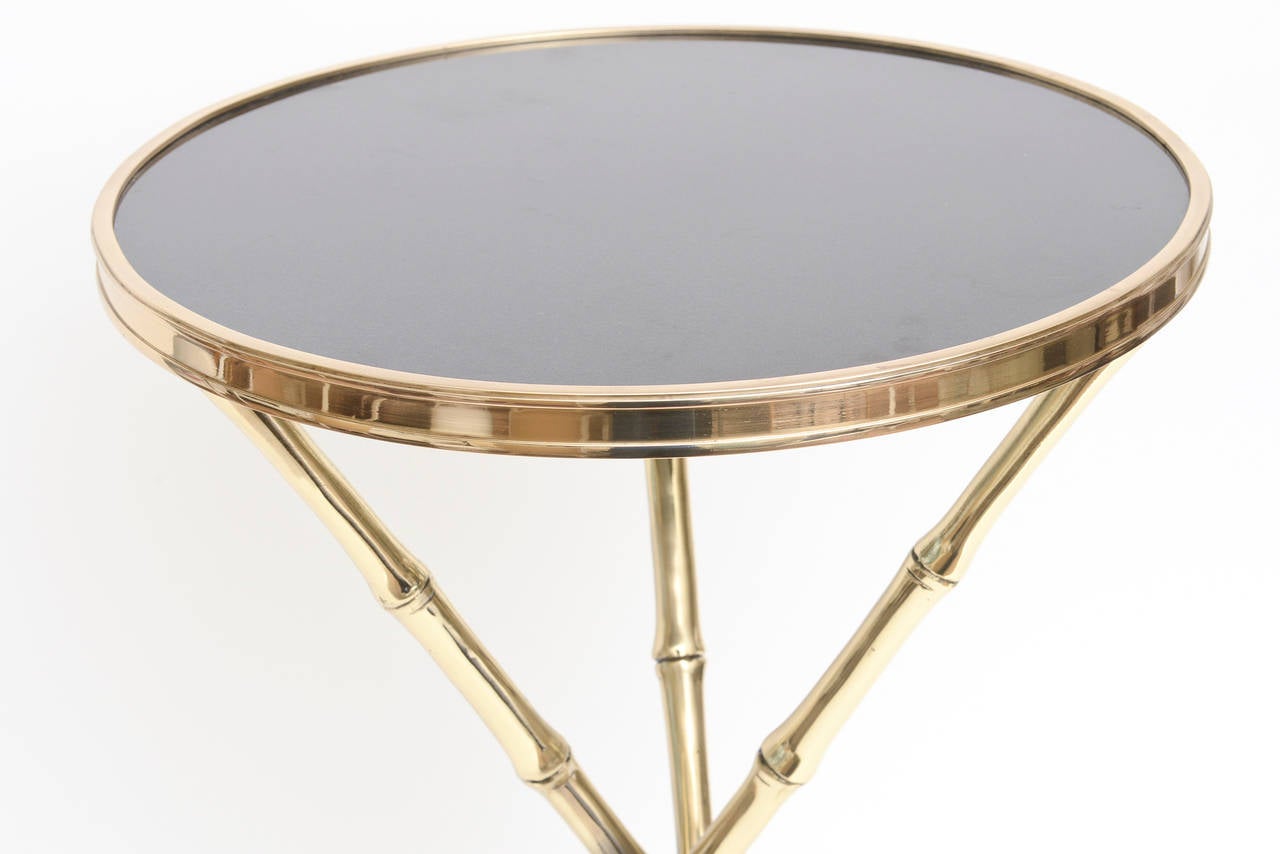 This Italian moderne yet versatile side/drink table has a black granite top and polished brass
legs and perimeter.
The detail of the faux bamboo and the braided ring around the middle portion
lends dimension.

This is forever and classic!!!