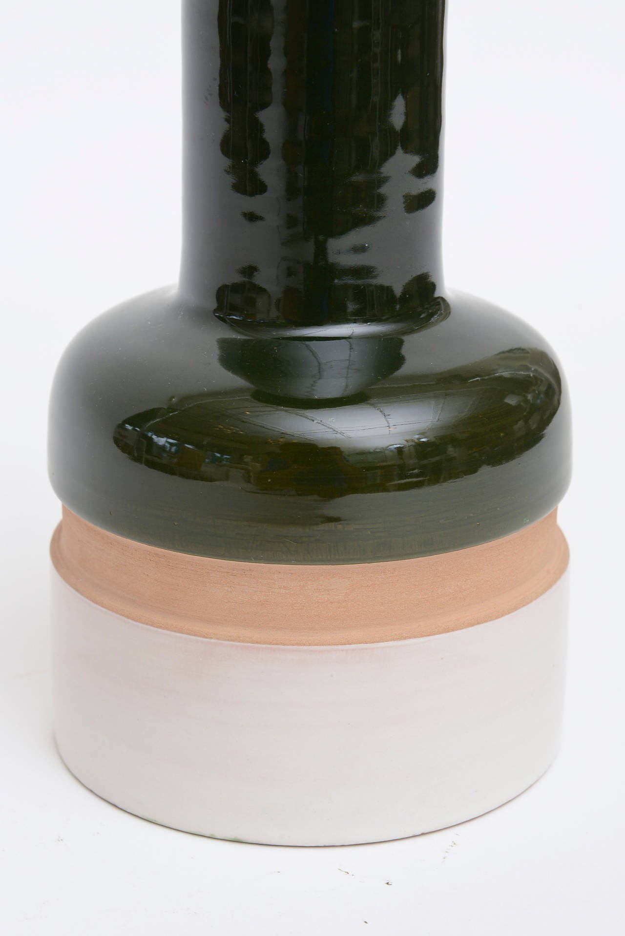 The wonderful glaze of the ceramic in rich dark hunter green meets the unglazed tan meets the glazed white bottom. It has all the original Italian labels on the bottom.
This was made by Ettore Sottsass for Raymor in Italy. 
It is architectural in