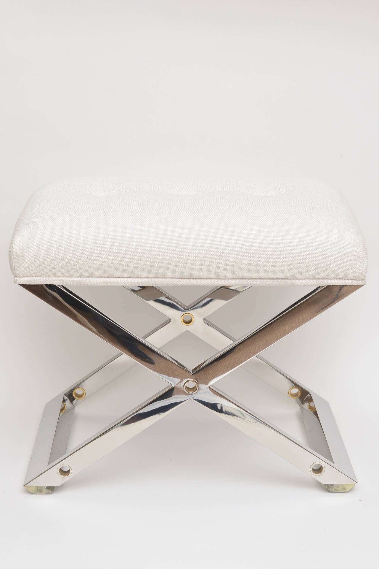 This moderne chic and timeless X-framed bench attributed to Karl Springer is chrome-plated steel and brass holed inserts. It is wonderful for a vanity, bedroom and even a closet.
It has been newly upholstered with a fine white silk or linen weaved