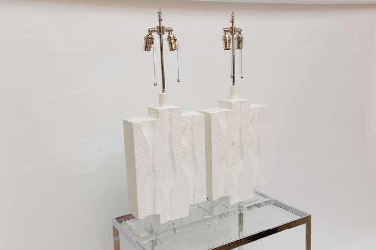 These amazing and unusual pair of white plaster of paris lamps have all been redone... chic, sculptural and architectural.
They are in the style of Serge Roche. Their architectural intaglio design on both sides in the plaster lend to their