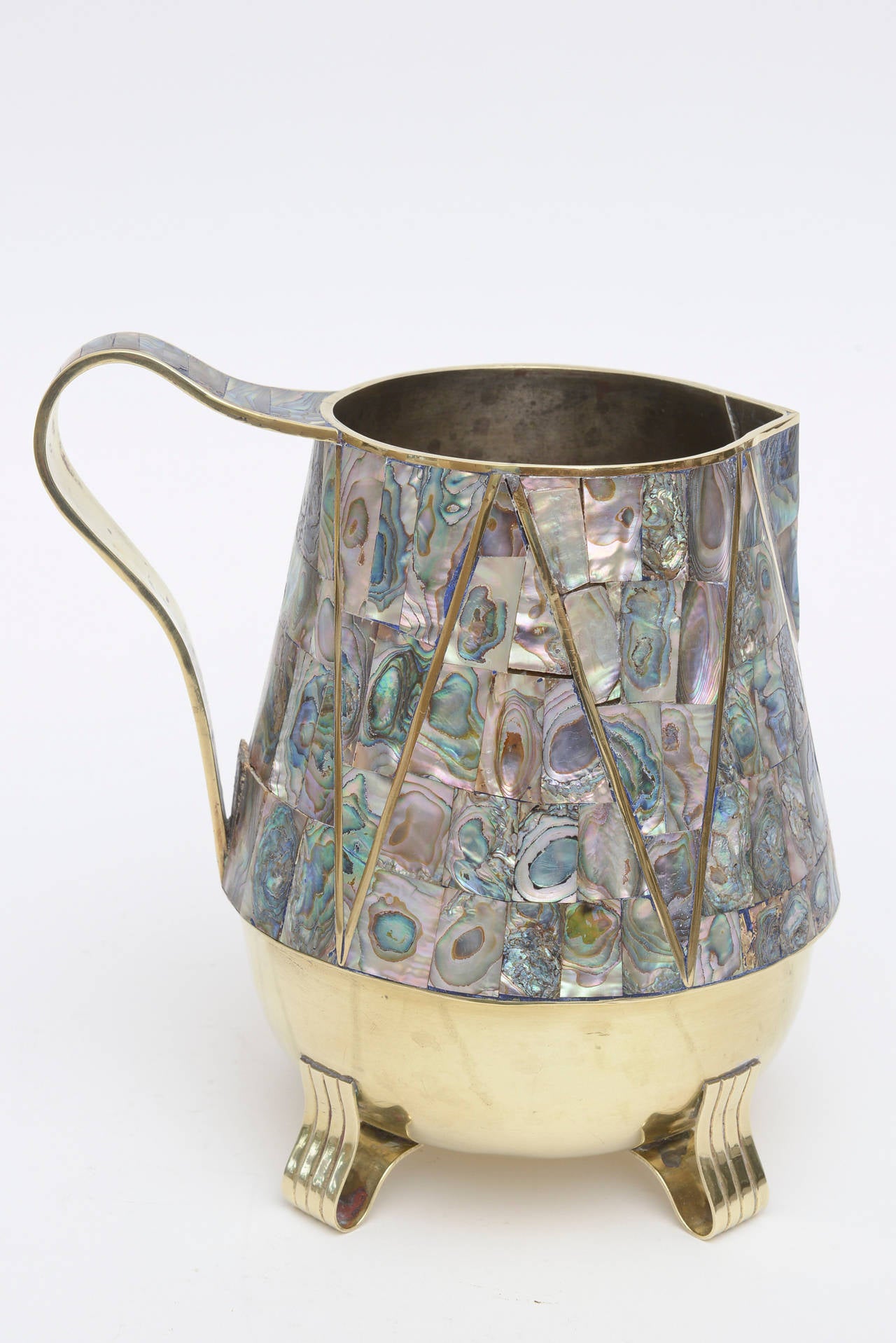 The abalone is so rich against the polished brass of this hallmarked Mexican
Pitcher or vase or vessel. It is in the style of Salvador Teran and has two letters inscribed on the bottom alone with Taxco. The letters are JI or TI.
It is Mid-Century