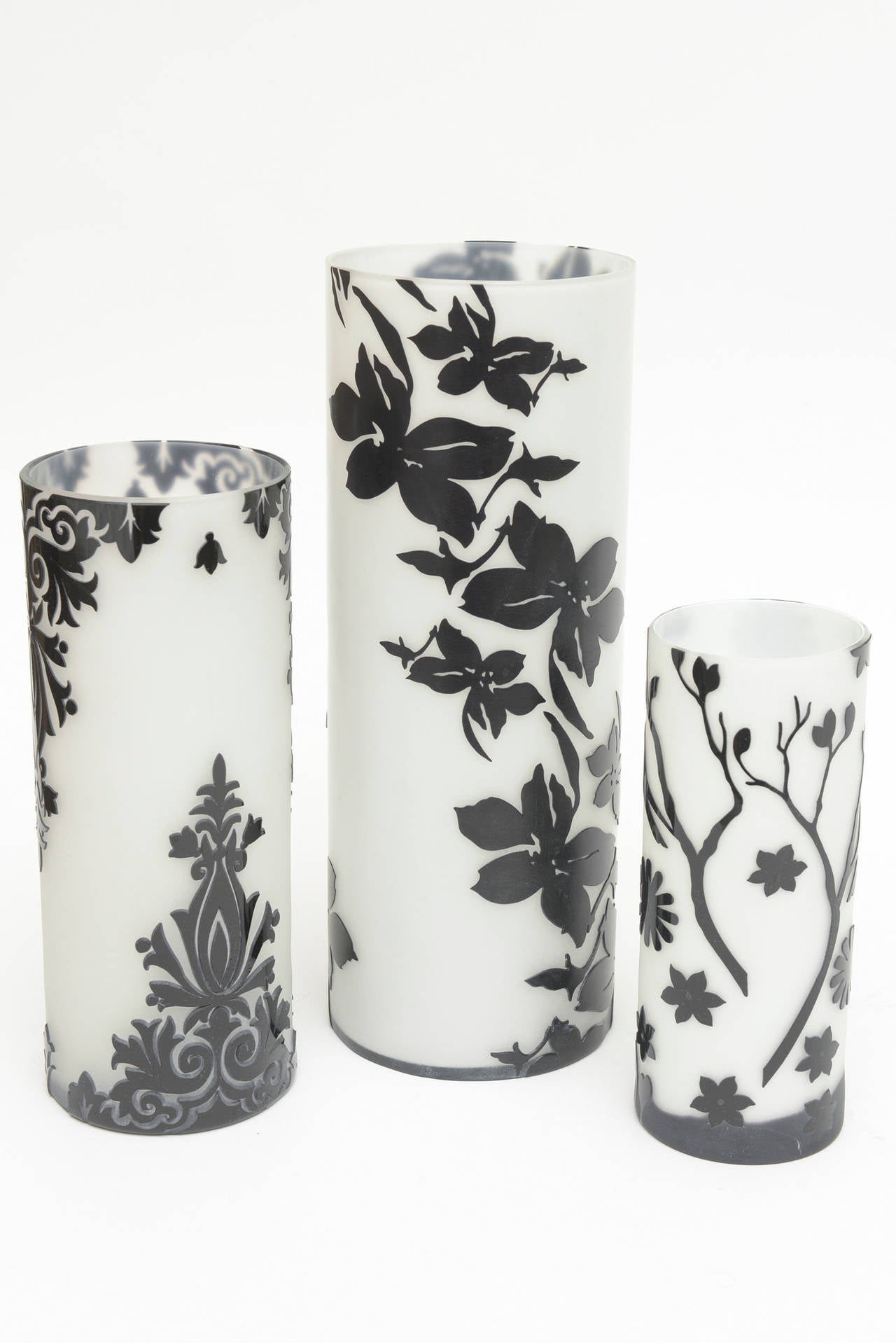 The dimensional different patterns raised relief of the black against the opaque white glass make this trio of cameo glass vases so dramatic. The patterns range from flowers to birds and flowers to fleur-de-lis. It is cut glass in cameo form.
They