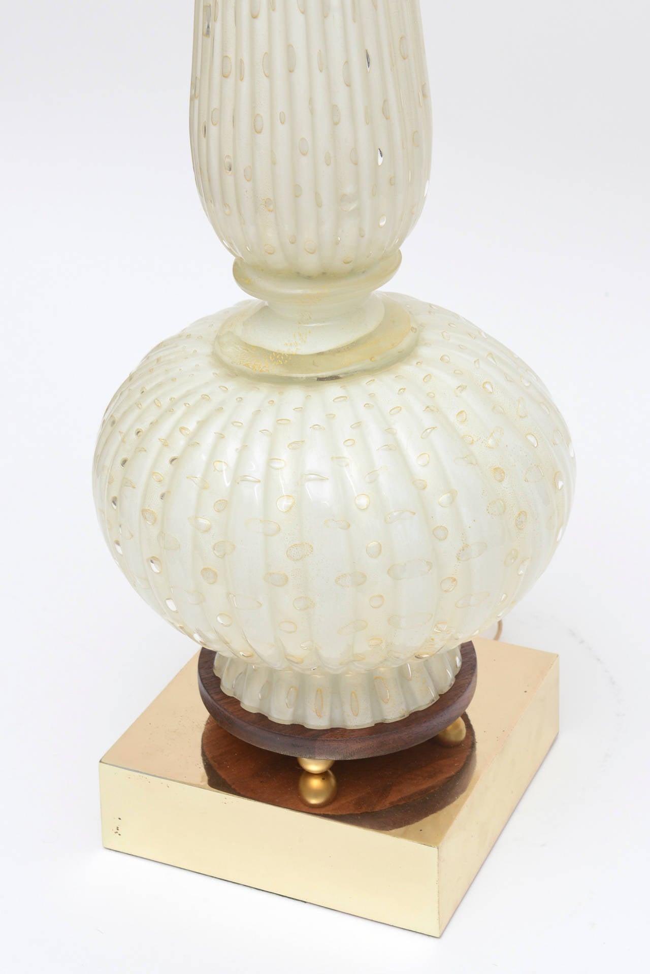 The sensual form of this very tall magnificent 1960s Barovier e Toso Murano glass lamp has beautiful gold aventurine almond and round shaped droplets throughout the lamp. There are two gold glass disks in the center. It sits on a brass square base