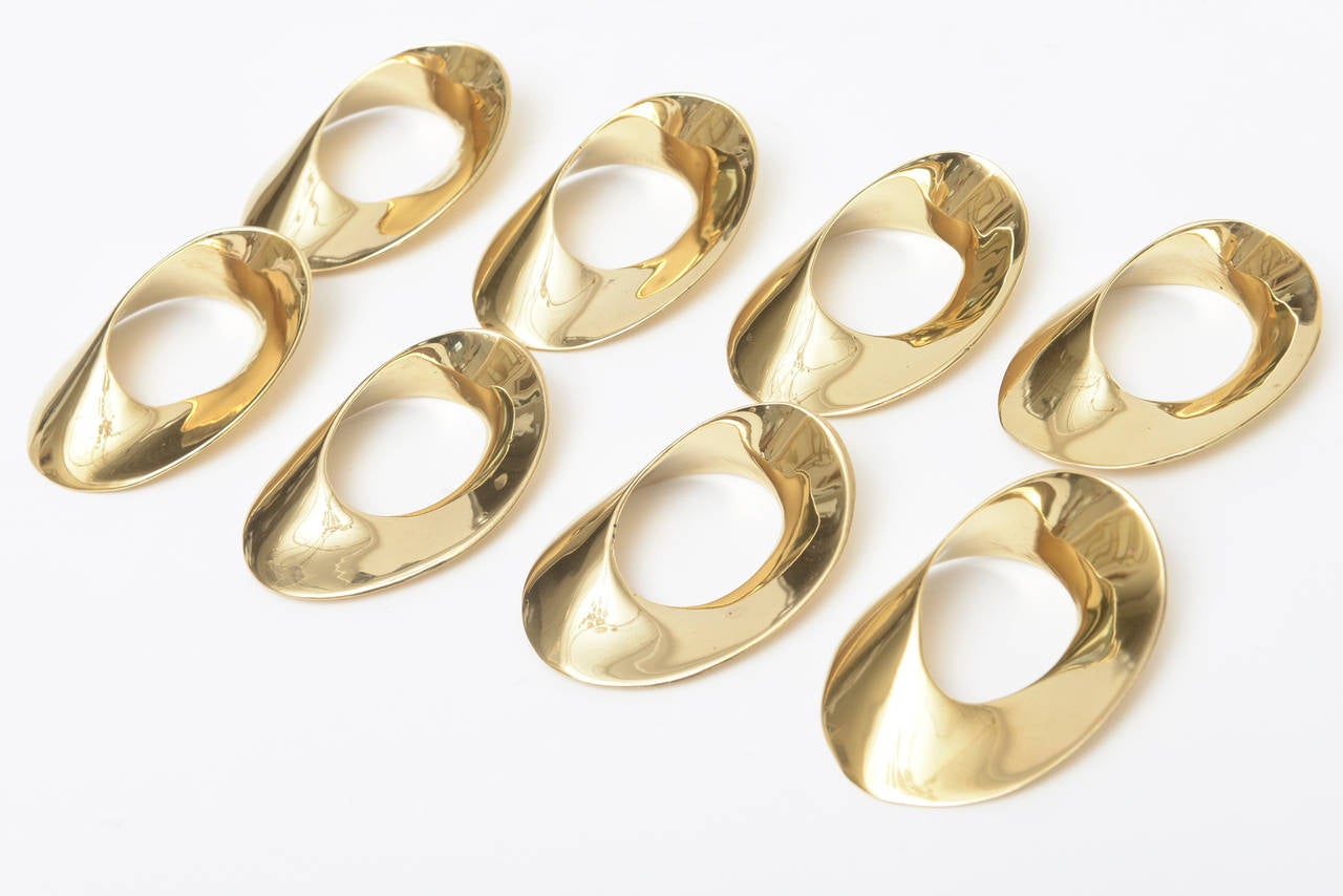 These fabulous set of 8 brass Mid-Century Modern napkin rings are both sculptural and elliptical. They look like mini bangle bracelets. They were once professionally polished but now have a patina on them from air. We will not be polishing them