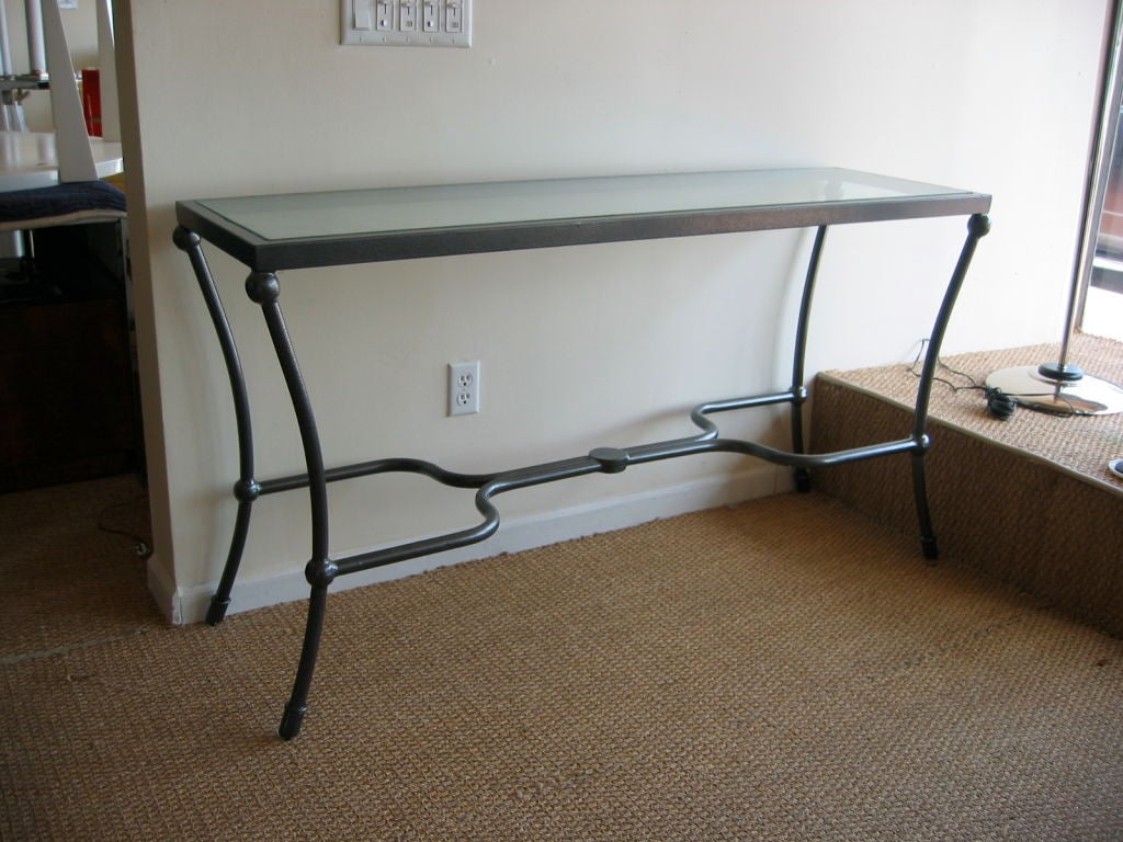 Steel console table with a powder coated greyish finish and glass top resting on a lip for a flush top surface.