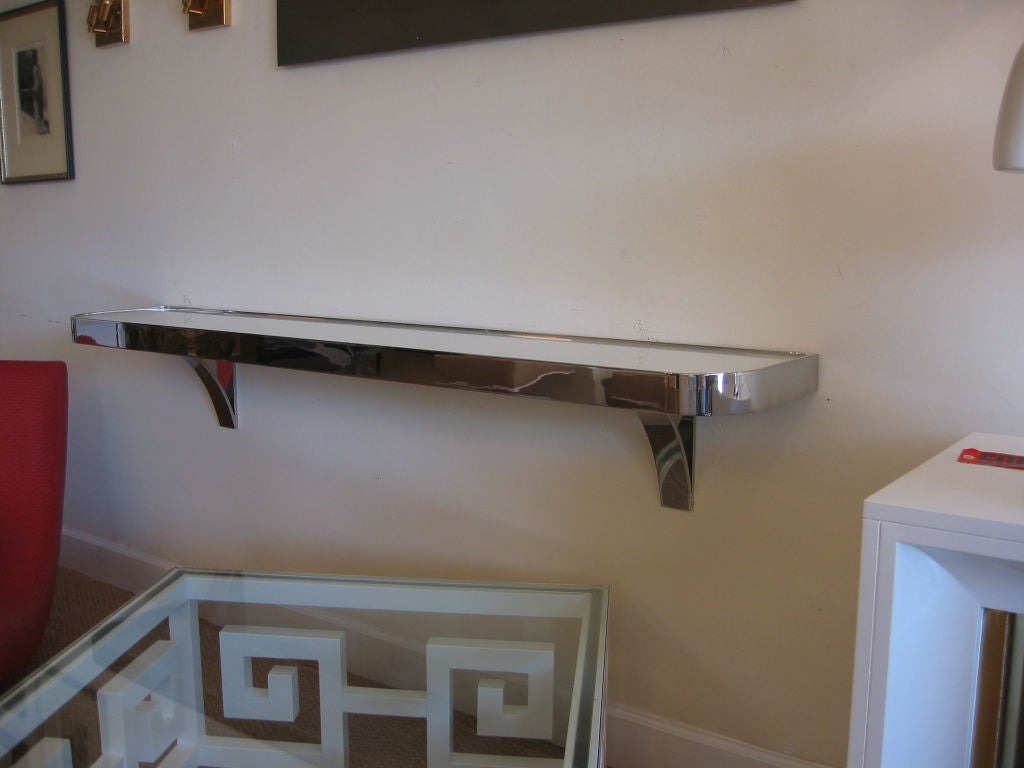 High polished steel wall mounted console with white glass insert. Fantastic in an entrance way. Designed by I.M. Rosen; the brother of Leon Rosen. Chic, simple Modern and functional. It is called  the #3202 console.
