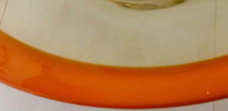 The thick rim of hermes orange makes this wonderful Italian Murano glass monumental oval bowl/platter  gorgeous and utilitarian... The process is called incalmo. Seguso is the maker...
The bottom is flat and polished.