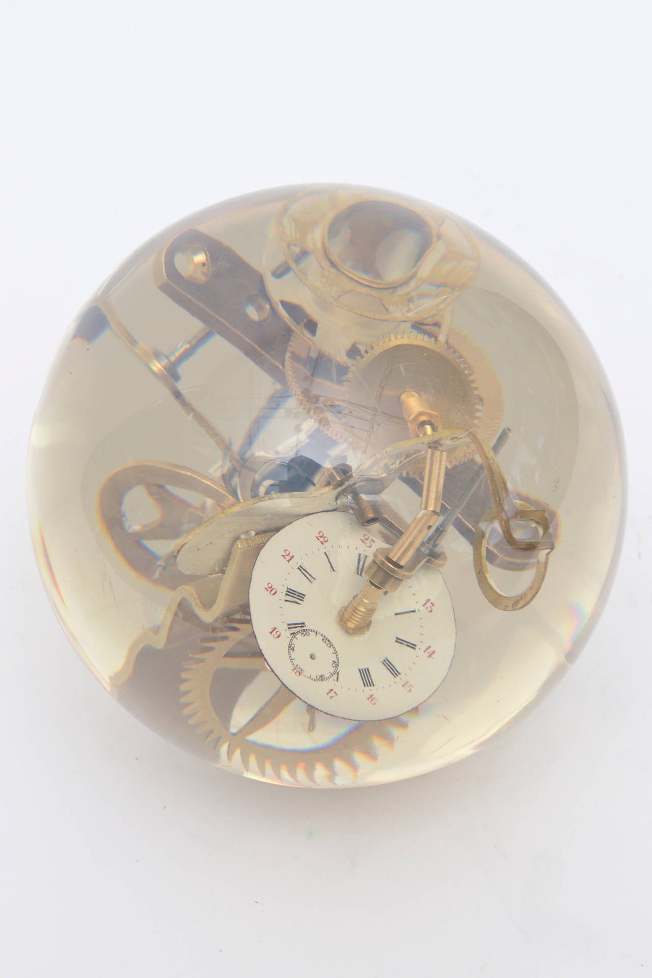 What a great piece for a man's desk or cocktail table is this vintage French Lucite and brass embedded round ball sculpture. Many brass parts of gears and clock parts are embedded and floating in this embedded ball that sits on a brass base.