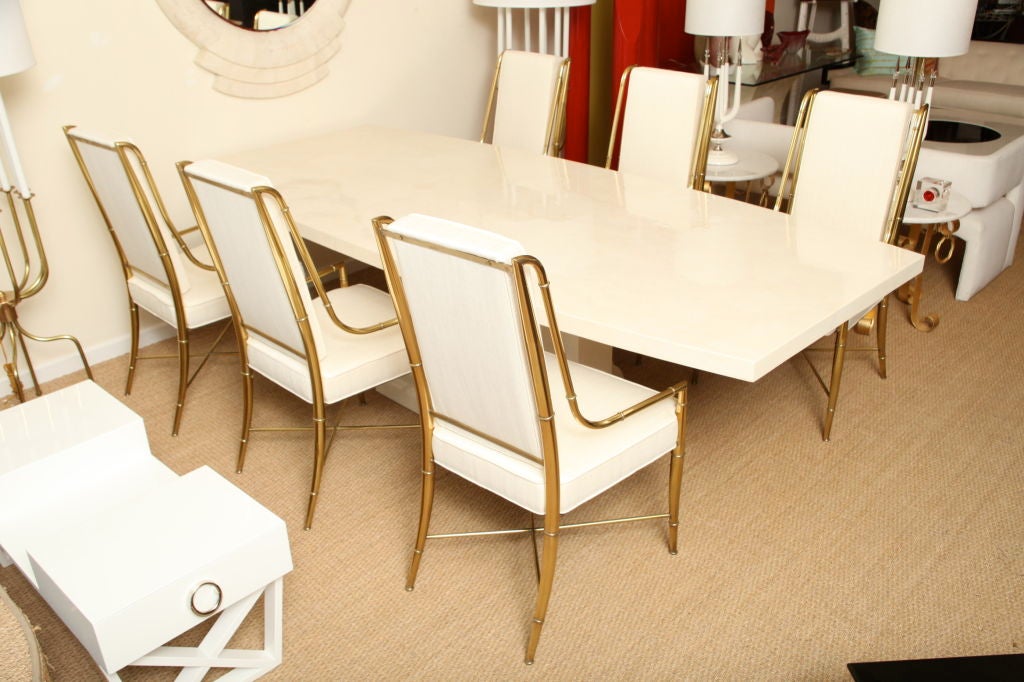 This monumental lacquered goatskin dining room table is in the style and influence of  Karl Springer. The impressive tabletop features luscious cream to ivory tones of goatskin and is anchored by an Art Deco inspired meets 1980s pedestal base. The