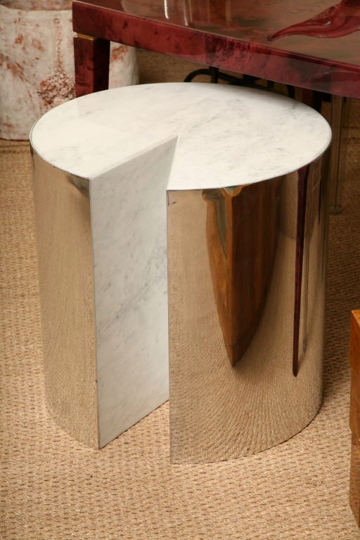 This sensational table features a  Carrera marble top and internal wedge panels. The frame is wrapped in highly polished metal sheeting and the bottom is adorned with castors to provide easy movement.   It is a perfect accent table and adds interest