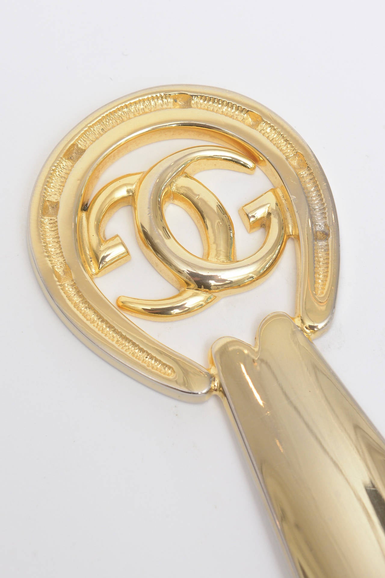 Classic and vintage is this Gucci horseshoe GG gold plated over nickel shoe Horn or desk accessory/ paperweight. It has great weight to it. It is hallmarked on the front... made in Italy.            
At the widest part of the Gucci emblem it is