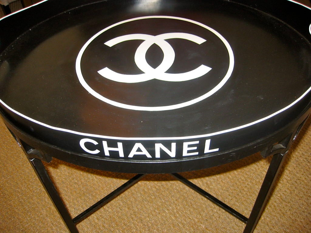 This iconic tray top table is the ultimate in style and refined elegance!  It features the classic Chanel emblem and logo.  This was used in the Paris Chanel boutiques in the late 1980's.  It is a painted iron black base with a removable metal tray