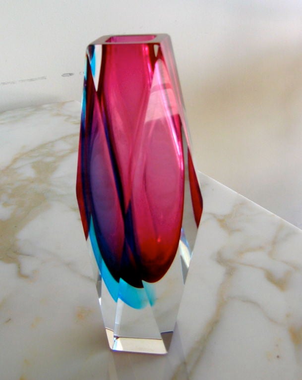 This faceted and formed Murano glass vase is stunning with its vibrant jewel tones.  A pink glass midsection is swirled with a bright turquoise blue accent and the combination forms luscious shades of burgundy, pink and purple. it is signed