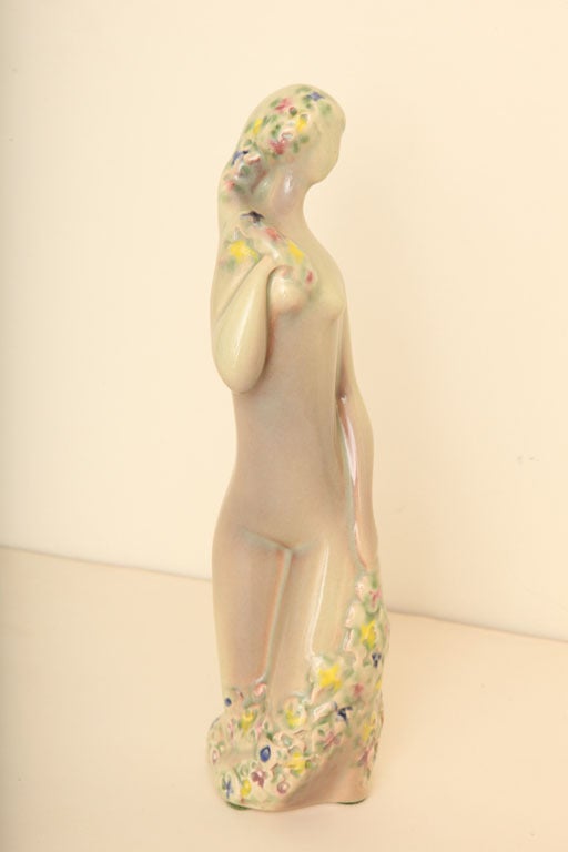 This Art Deco glazed ceramic sculpture has drapery of flowers cascading over the woman's body. It is the color of celadon with applied flowers in ceramic form of blue, yellow, pink and purple. Listing her at a very great price now. She has a number