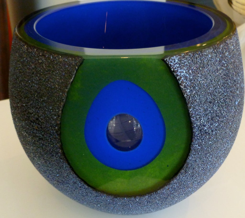 This amazing and gorgeous color of chartreuse green and royal blue and crushed glass chips makes this signed glass vessel a show stopper. It  has a bullseye center<br />
of the combined colors. The outside layer of glass is textural with a bumpy
