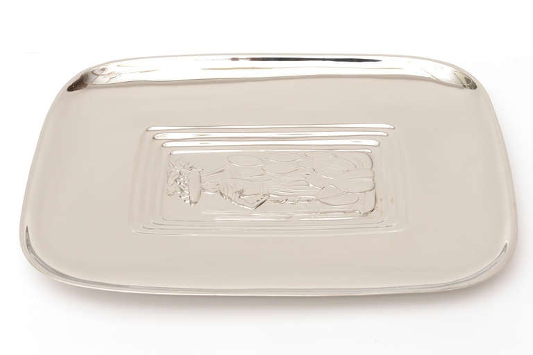 Exotic depictions of embellished and embossed Diego Rivera imagery are the centre of this polished silver-plate serving tray. The recessed steeped lines framing the inside imagery add dimension and form. it is signed on the back and numbered