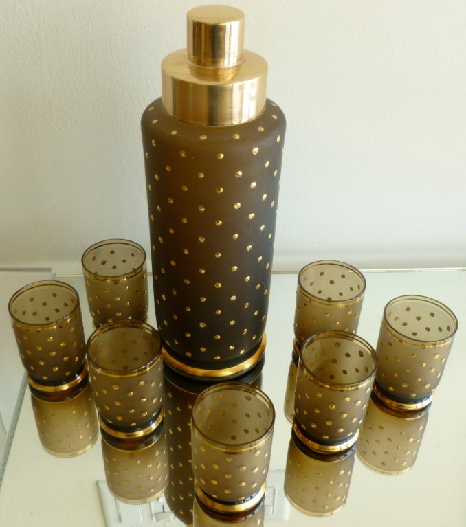 This amazing  and unusual brown glass and doted 22 carat gold overlay martini shaker and 7 cordial glasses set make a show stopper statement for a bar or even coffee table.The top of the shaker has been polished, as it is brass. The brown glass of