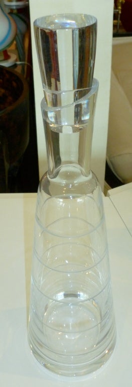 This chic modernist, heavy clear crystal glass decanter with its circular raised design is perfect for any bar. The wonderful stopper is perfect and moderne. It is made in Slovenia for Christofle. It is from the 1970s and is signed. Sorry the photos