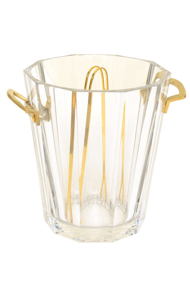 This very substantial, heavy  and elegant Baccarat crystal ice bucket and or champagne holder/cooler is timeless and elegant.The  mounted and polished bronze handles and the original brass ice thongs along with the fluted glass make a simple and