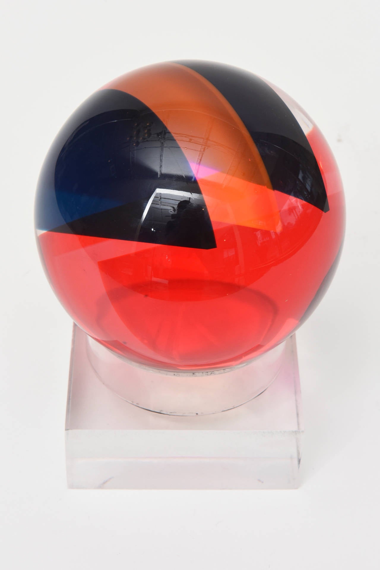 The intersecting planes of colored laminated Lucite in this fantastic signed Vasa round ball Lucite sculpture changes color with each angle and placement of the ball. It sits on a Lucite stand that is fitted for this ball. It has so many variances