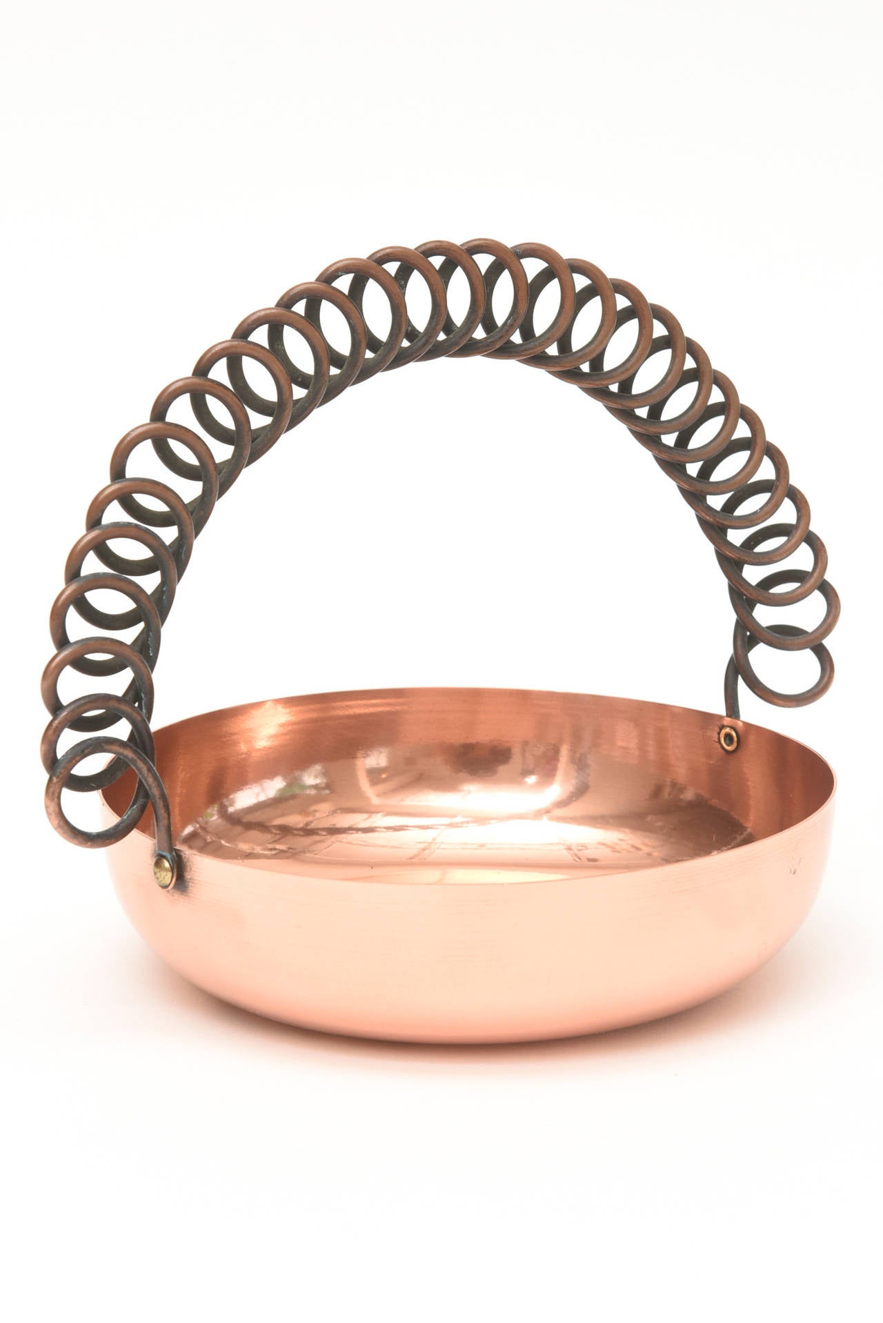 This vintage polished copper small bowl that has the sculptural looped handle is hallmarked Rebajes with it's symbol. The looped metal handle is another form of darkened metal. An unusual Mexican bowl.