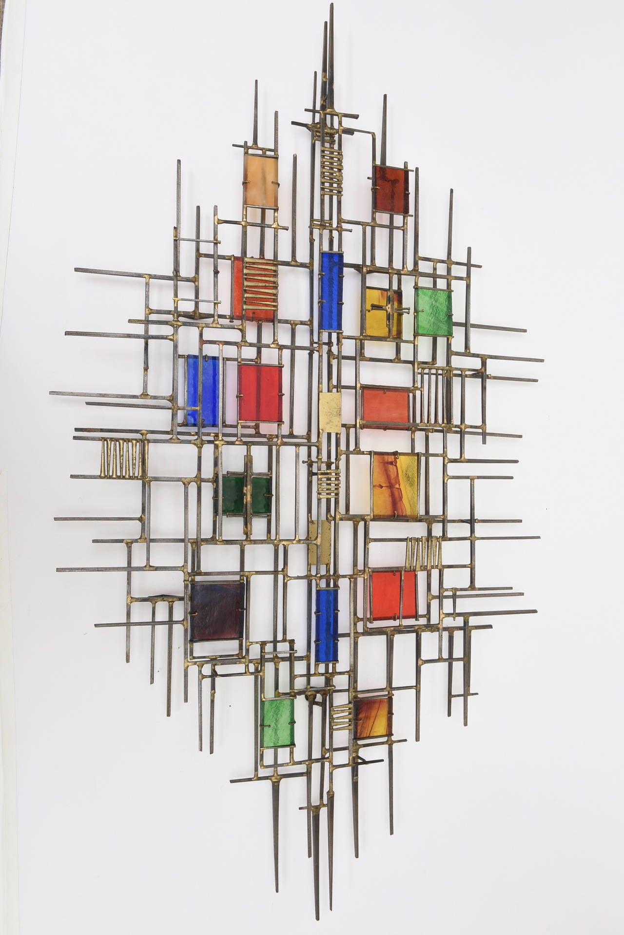 This amazing rare, brutalist and modernist wall sculpture attributed to Coffey is hard to find. The glass panels in a myriad of colors is amazing set against the brass and nails. Truly a piece of art! Even some of the glass panels have a rainbow