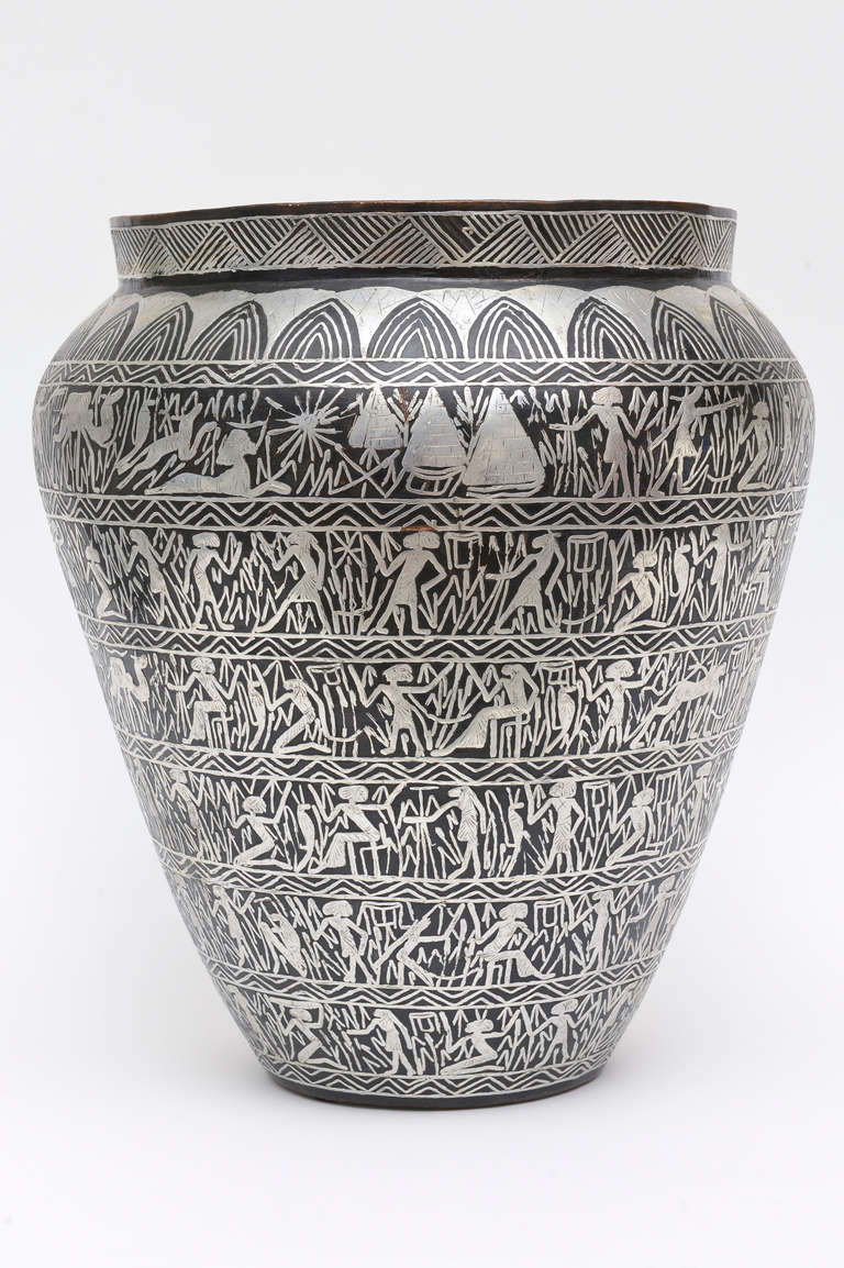 This monumental unusual vase/vessel/sculpture storybook tale in relief form of silver overlay of amazing Egyptian characters  in row after row form relays a story.
it rings Art Deco meets Egyptian revival.
Looks like it belongs in a reference