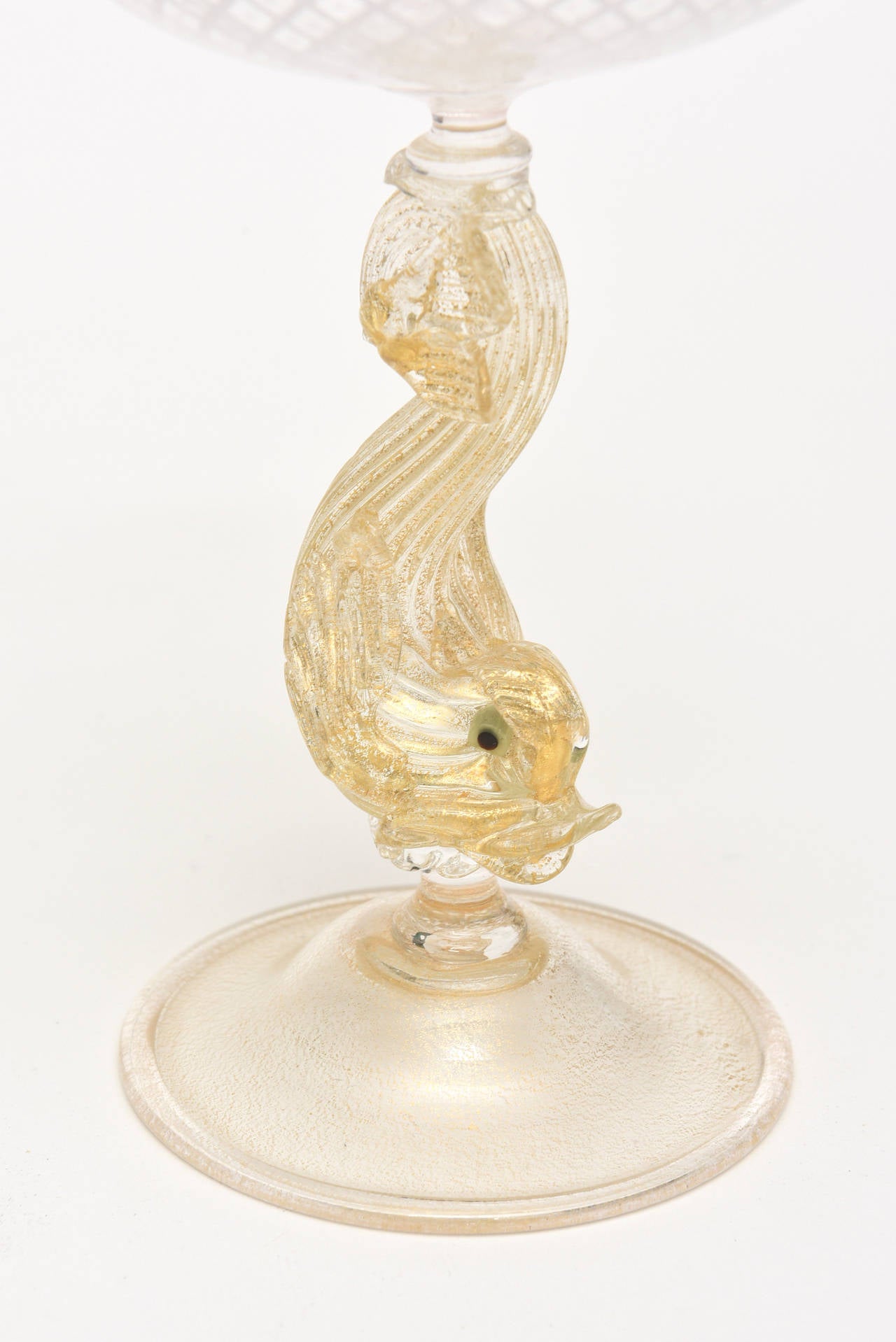 These elegant handblown period gold aventurine and white Reticello criss cross goblets are by
Salviati.
The stem is a dolphin/undine in the metaphysical sense with a black glass eye.
The lovely criss cross pattern of the white reticello or