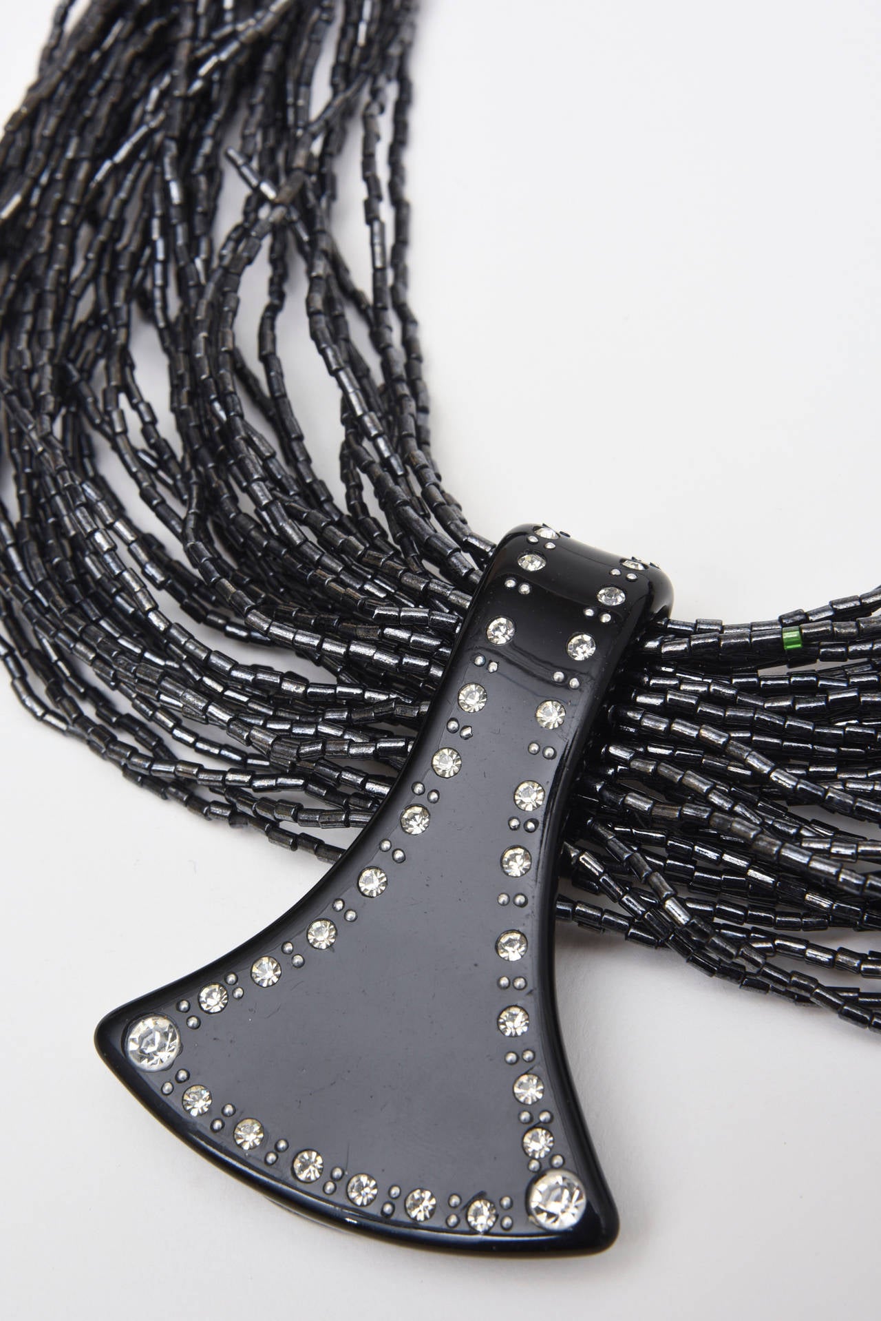 This dramatic and collectable signed Italian Ugo Correani necklace is au courant. It is comprised of hundreds of tiny linked black glass beads in many many strands with a lucite and rhinestone pendant. The sculptural end is a black lucite studded