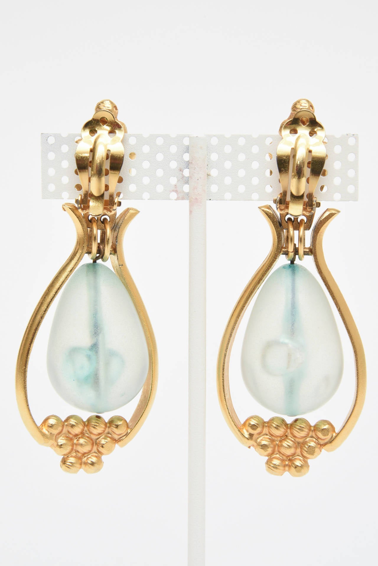 This pair of lovely 1980's clip on earrings are gold plated with a ethereal blue light turquoise resin drop in the center. They are modern, elegant and make a statement. Very beautiful on. These are perfect for any season but especially summer,