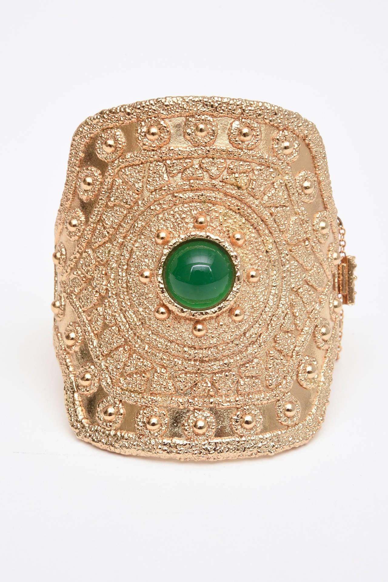 This showstopper of a vintage signed Napier cuff bracelet with textural raised design of warrior meets Egyptian Revival cuff is definitely a conversation piece. There is a green glass stone in the center. It is gold plated. It has good weight to it