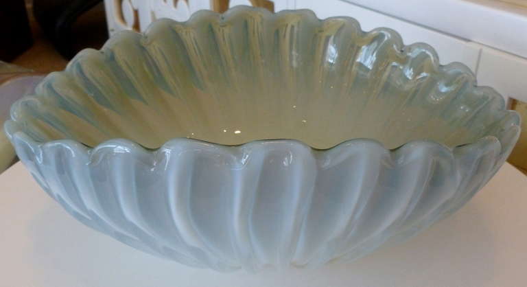 The colors of gray blue meets opalescent and pearlized white in this ribbed and  luscious bowl. When bathed in light, it becomes pearlized and changes color. Textural thick ribbed glass graduates in size and the elegant scalloped rim gives this