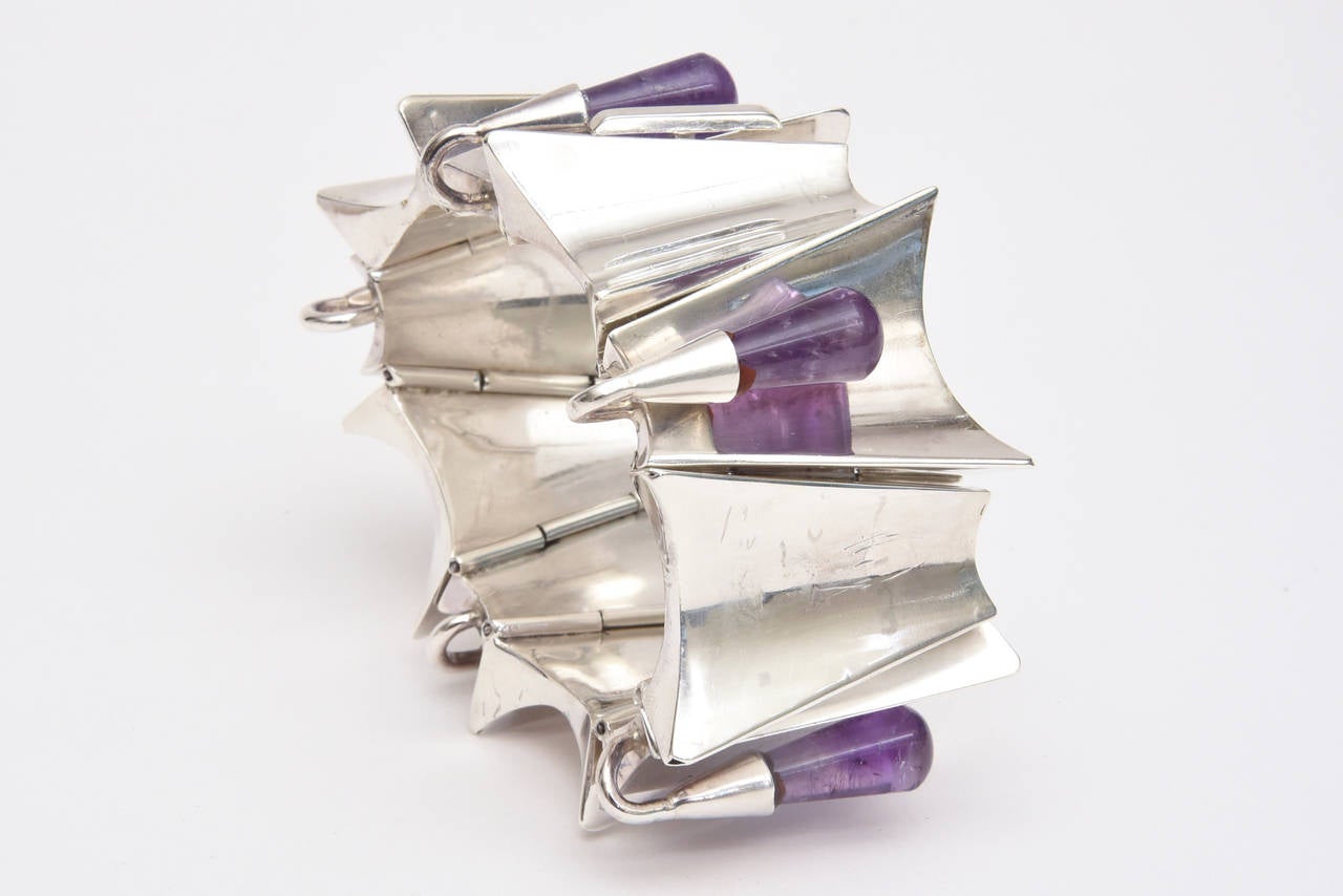This fabulous hallmarked sterling silver and amethyst cuff bracelet has modernist sculptural pieces of sterling silver that look like inverted jagged edges set  with amethyst drops with a silver top. It is marked Sterling Mexico Margarita Taxco. It