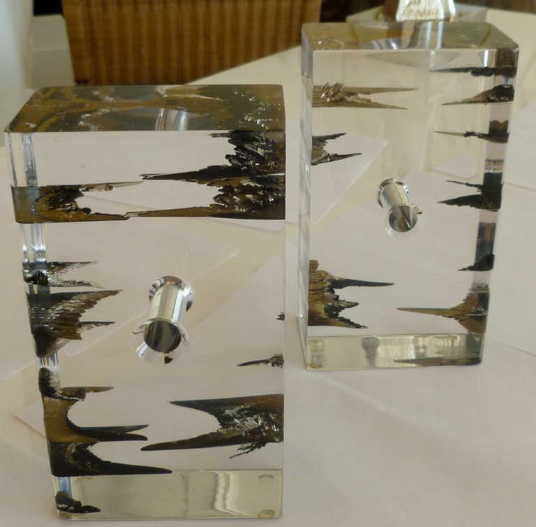 These fascinating bookends of encased pieces of floating brass and other elements inside the lucite of different forms and shapes give these pieces an artistic element. The original paper label that is worn but still intact says