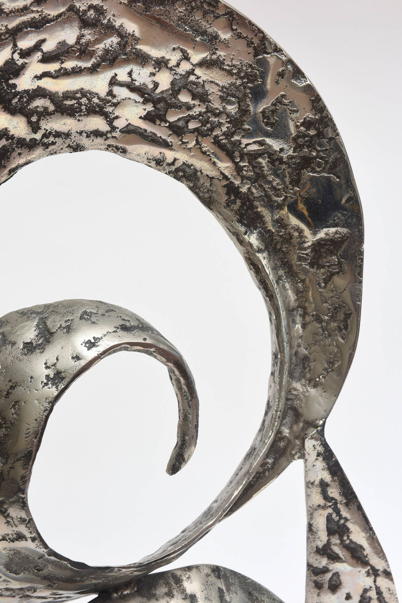 This Dual spiral abstract sculpture is hand-hammered aluminum with a black painted wash over it. In some ways it has a Brutalist feeling to it. It sits on a black marble base and is unsigned. It is handwrought and has texture and dimension... it is
