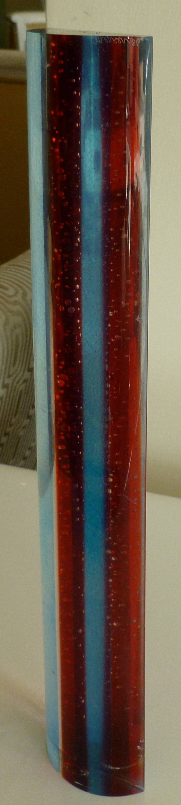 This wonderful signed Norman Mercer lucite tower sculpture dated '86 changes with the play of light. One red predominant line of red lucite is flanked by sky blue sides with the outer bands as clear lucite... in this narrow but tall Norman Mercer